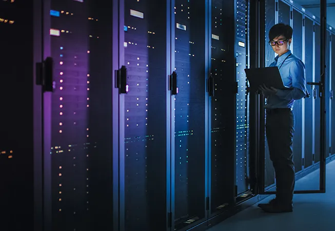 data center with man working at computer checking on server status